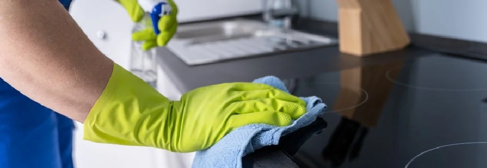 Person reinigt Herd mit Lappen